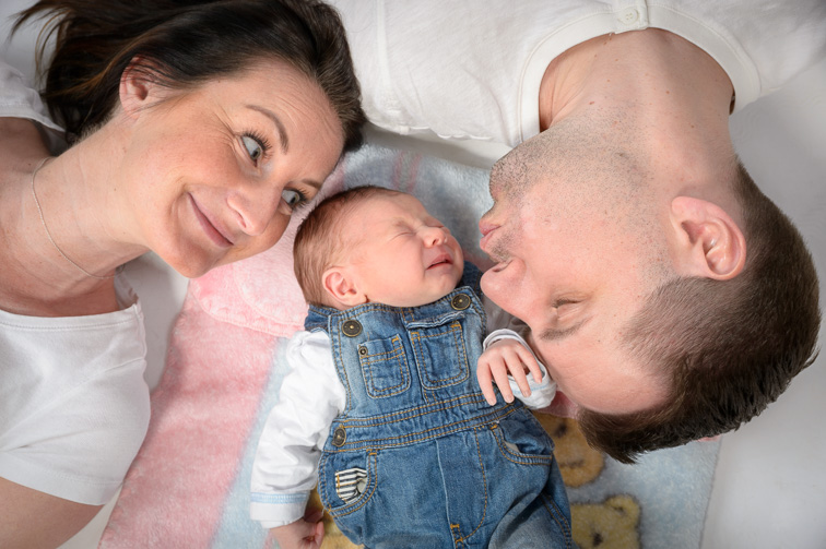 Eltern liegen mit ihrem Baby auf dem Boden, natürliche Babyfotografie in Villach