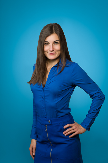 Modernes Bewerbungsfoto einer Frau im Studio mit blauem Hintergrund und Halbportrait