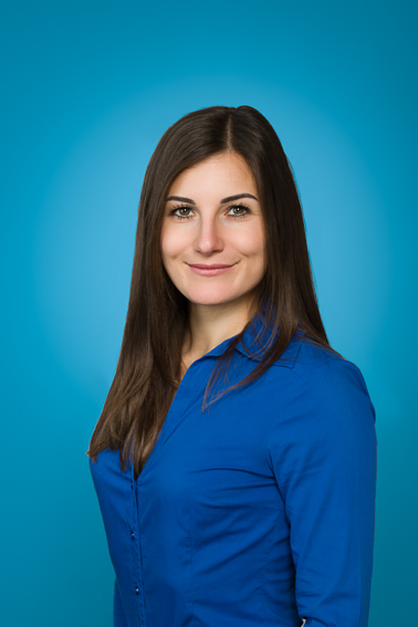 Modernes Bewerbungsfoto einer Frau im Studio mit blauem Hintergrund und Brust-Kopf-Portrait