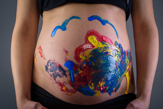 Nahaufnahme eines bemalten Babybauchs mit bunten Farben im Studio