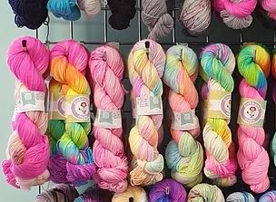 A row of multi coloured yarn skeins in vibrant pinks, greens, yellows.