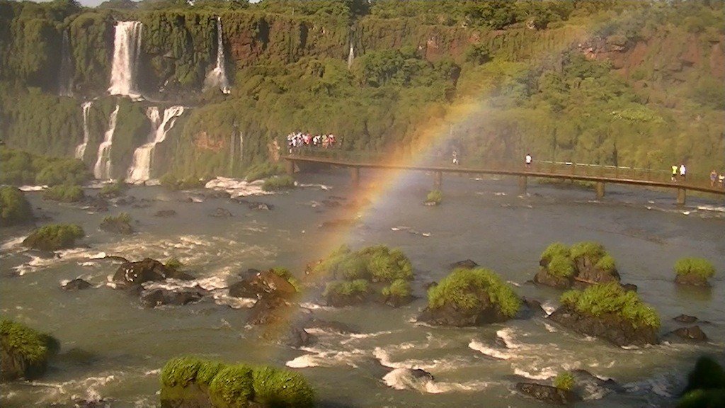 滝に近づく遊歩道の向こうに虹がかかっている