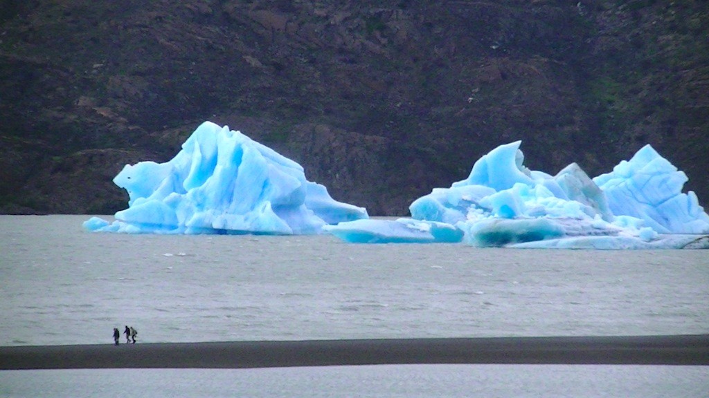 グレイ氷河から崩れ落ちてグレイ湖に浮かぶ氷山　手前の人達が小さく見える