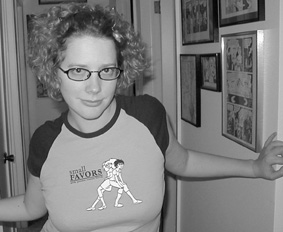 Junge Frau mit blonden Locken und Brille, enges stylishes T-Shirt mit Aufdruck eigener Comic-Zeichnung