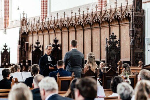 Brautpaar mit Gästen im Dom während der Trauung