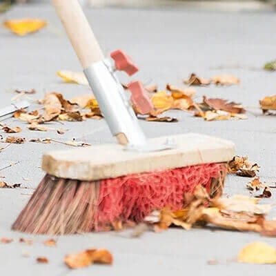Lichtschachtabdeckung wird mit Besen abgekehrt