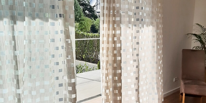 Moderne Gardinen für große bodentiefe Fenster in einem hellen Wohnzimmer