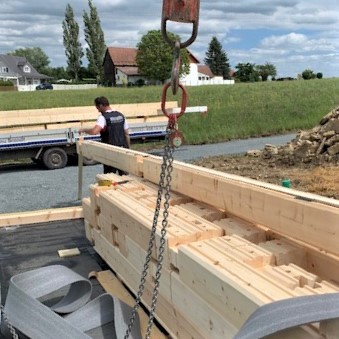 Die ersten Bohlen des Holzhauses in massiver Holzbauweise wurden genau positioniert