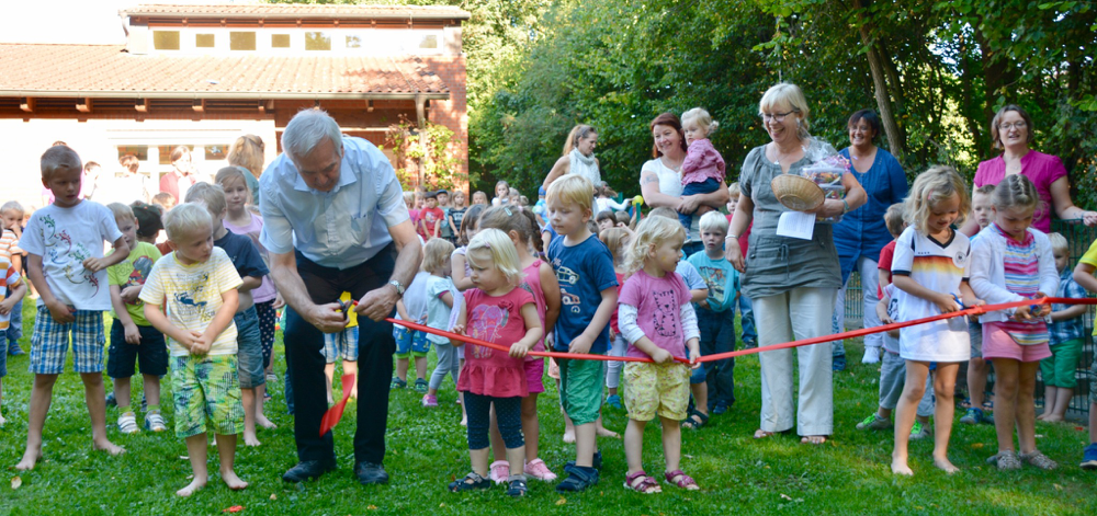 Bürgermeister Hans-Heinrich Barnick gibt den Spielplatz nach dem Durchtrennen des Absperrbandes frei.