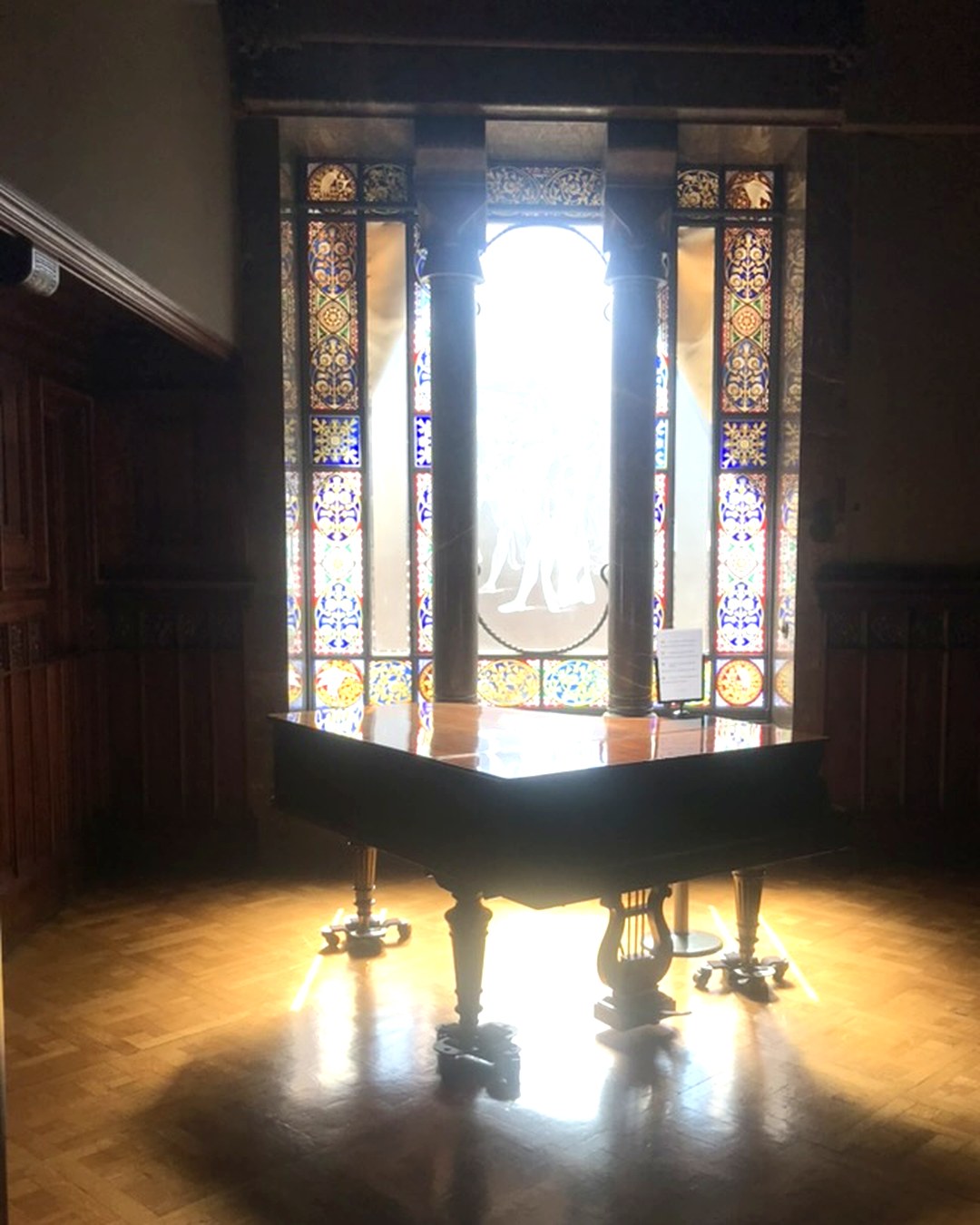 Pianoforte a coda davanti alle vetrate colorate del Palau Güell di Gaudí
