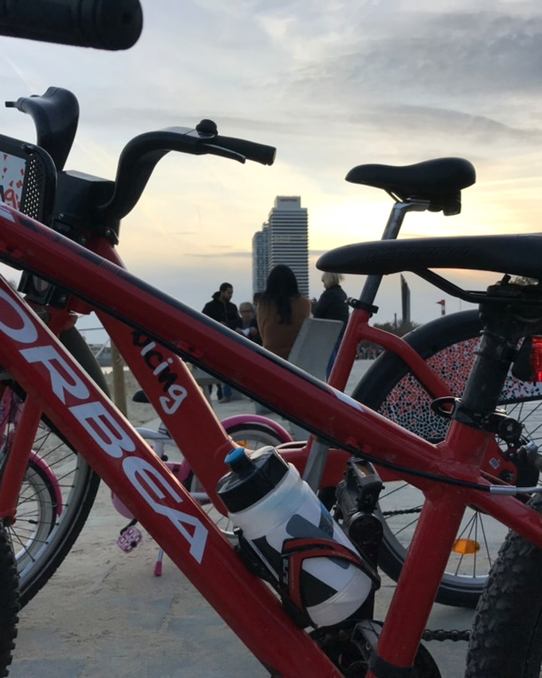 Biciclette rosse sul lungomare della Barceloneta al tramonto