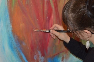 Frau malt zu einem persönlichen Thema in der Kunsttherapie ein Bild.