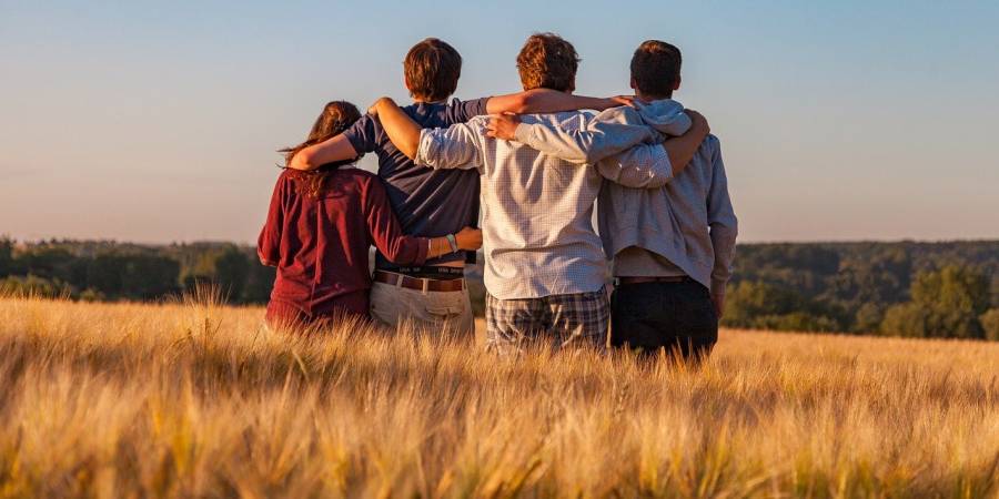 Vier Jugendliche Arm in Arm in einem Gerstenfeld (Symbolbild: Dim Hou)