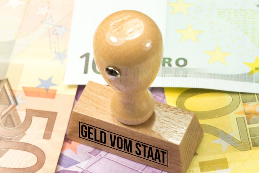 Euro Geldscheine und ein Stempel mit dem Aufdruck Geld vom Staat. Symbolbild: iStock/Stadtratte)