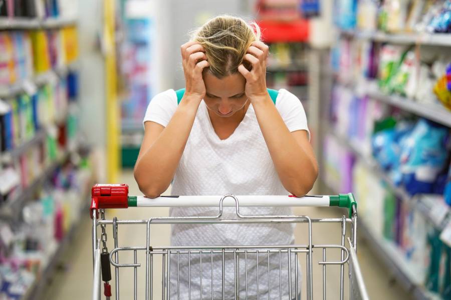 Eine verzweifelte Frau mit einem leeren Einkaufswagen in einem Supermarkt. (Symbolbild: iStock/Igor Vershinsky)
