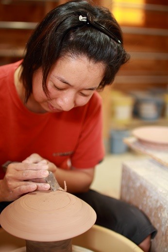 陶芸の制作技法のひとつ、ロクロでの削り作業をしているところ。湿台（しった）と呼ばれる台に伏せて裏側の余分な粘土を削り、均等な厚さにする。