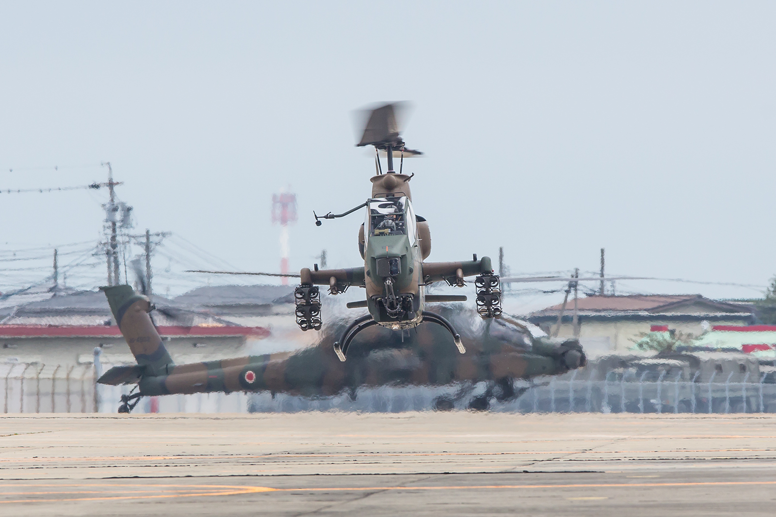 Eine AH-1S Cobra schwebt auf ihre Abstellposition, im Hintergrund ein AH-64DJP "Apache".