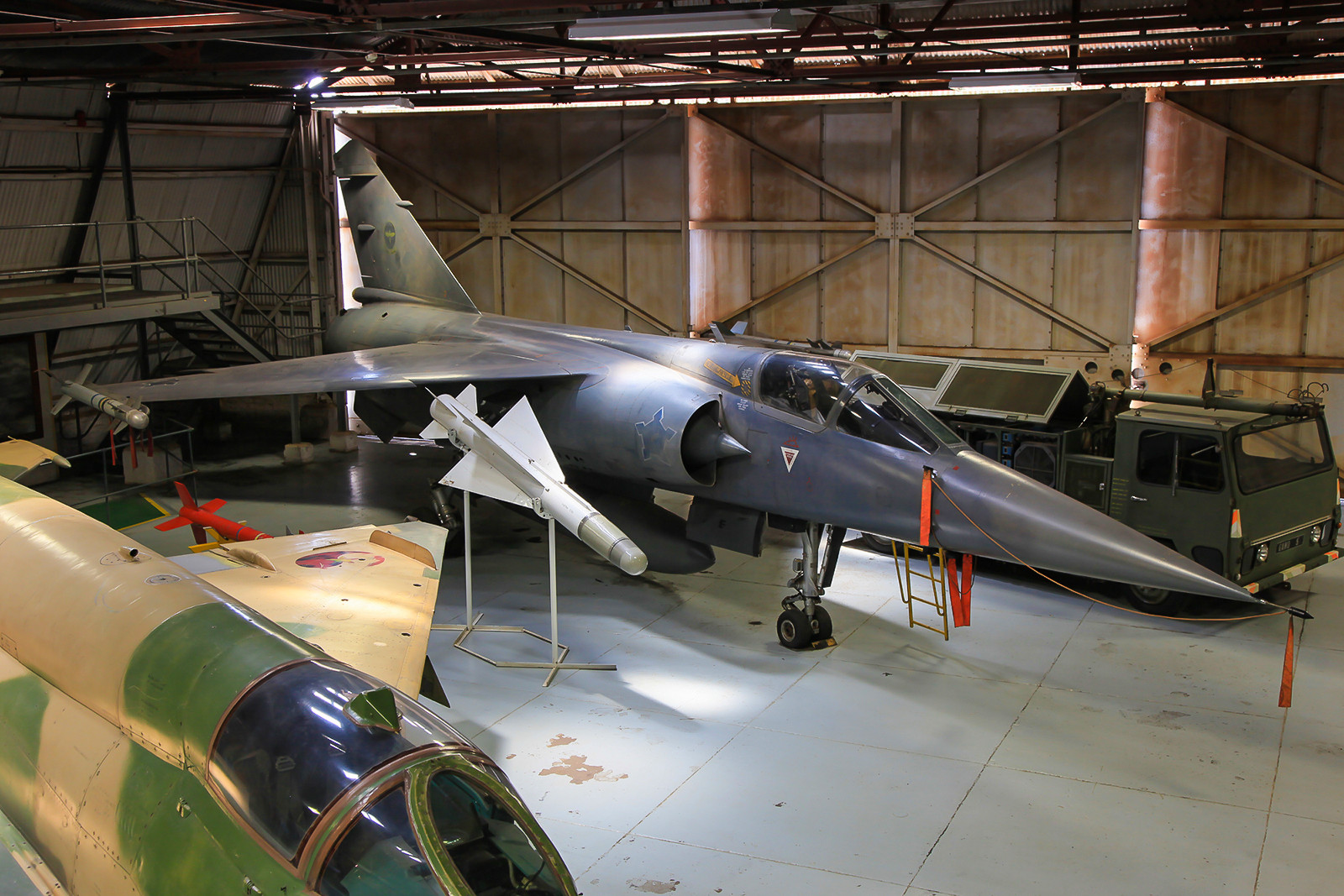 Etwas dicht zugeparkt, steht die F-1CZ mit der Nummer "203" in einem dunklen Hangar.