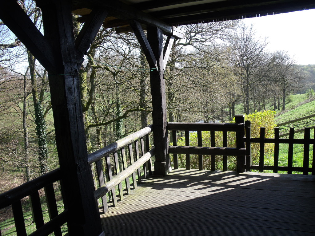 A terrace and lawns overlooking the valley with garden furniture and BBQ