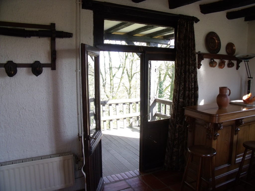 A terrace and lawns overlooking the valley with garden furniture and BBQ