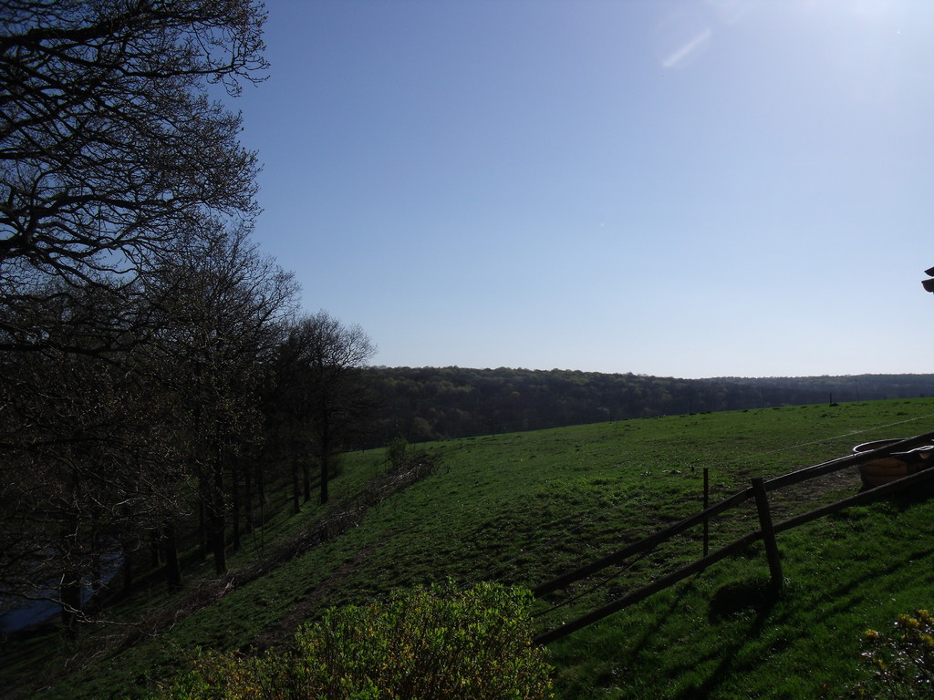 A terrace and lawns overlooking the valley with garden furniture and BBQ