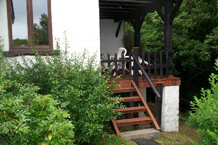 A terrace and lawns overlooking the valley with garden furniture and BBQ