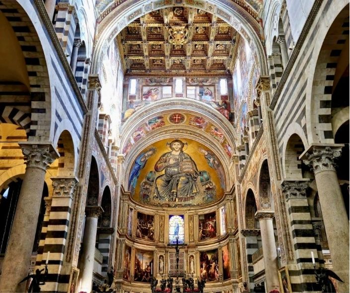 The interior of Pisa Cathedral, featuring striped marble arches, a golden mosaic of Christ in Majesty in the apse, ornate frescoes, and a richly decorated wooden ceiling.