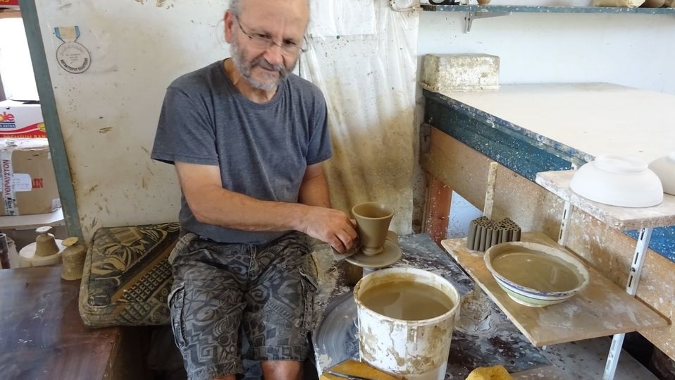 Sakis van de keramiekshop in Míli maakt een beker.