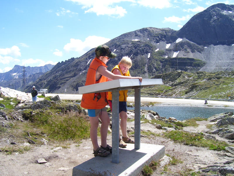 Mijn kinderen bestuderen op de Nufenenpashoogte de panoramakaart die aldaar is geplaatst. 