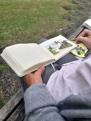 Kursteilnehmerin malt in einem kleinen Skizzenbuch in bad heilbrunn