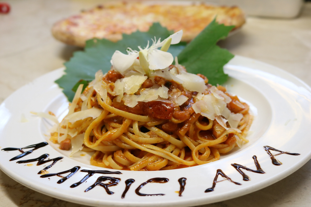 Linguini Amatriciana mit Speckwürfeln und Zwiebelstücken in hausgemachter Tomatensauce, mit sanfter Chilinote 