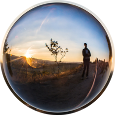 Mensch in Natur spiegelt sich in Glaskugel zum Sonnenuntergang