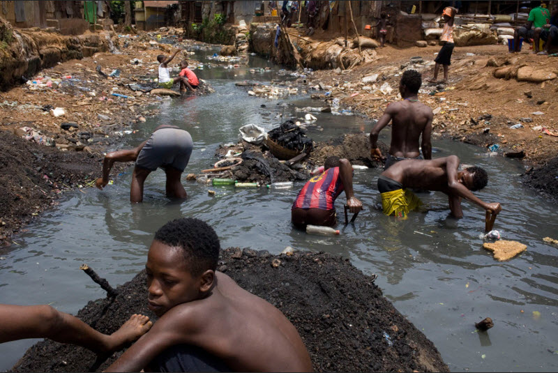 Ragazzi cercano qualsiasi cosa di valore nel fiume Crocodile nello slum di Kroo Bay a Freetown, in Sierra Leone