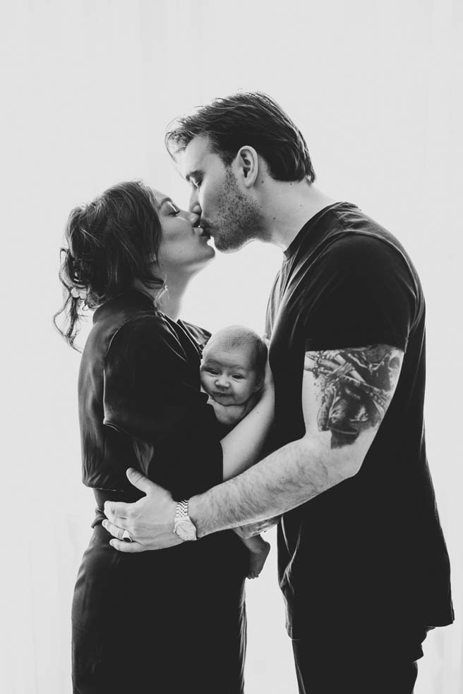 schwarz weiß foto mit jungen Eltzern die sich küssen und ihr Baby im Arm halten