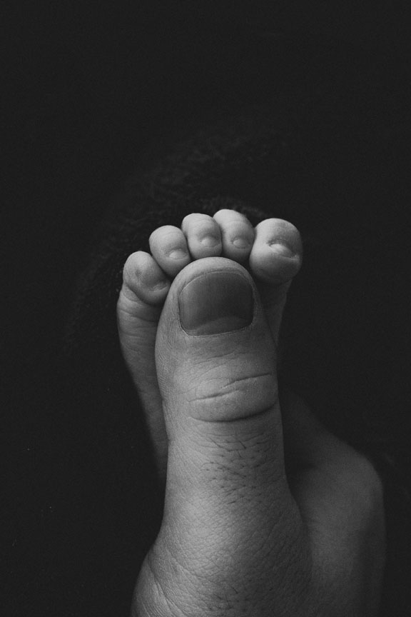 schwarz weiß bild von Babyfuss mit Daumen von Mama