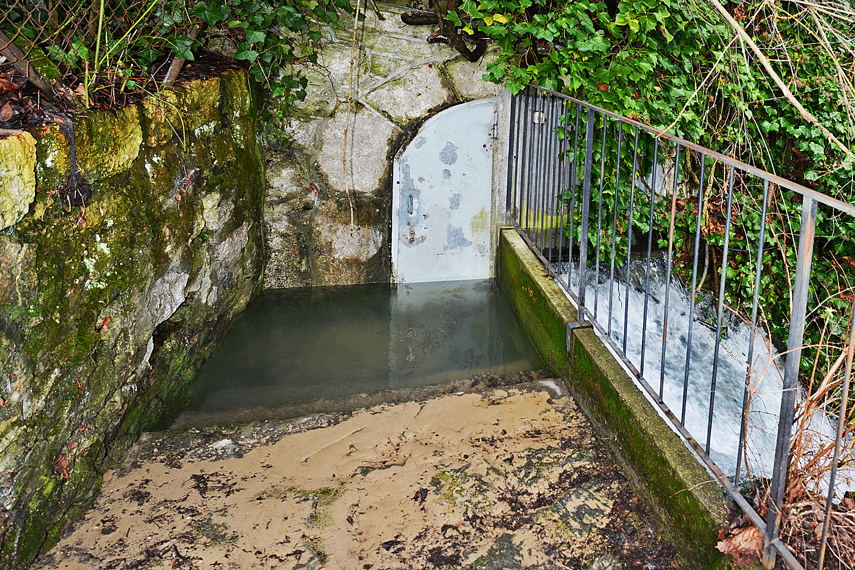 Eingang zur Quellfassung. Die Eingangstüre ist vom Wasser überschwemmt