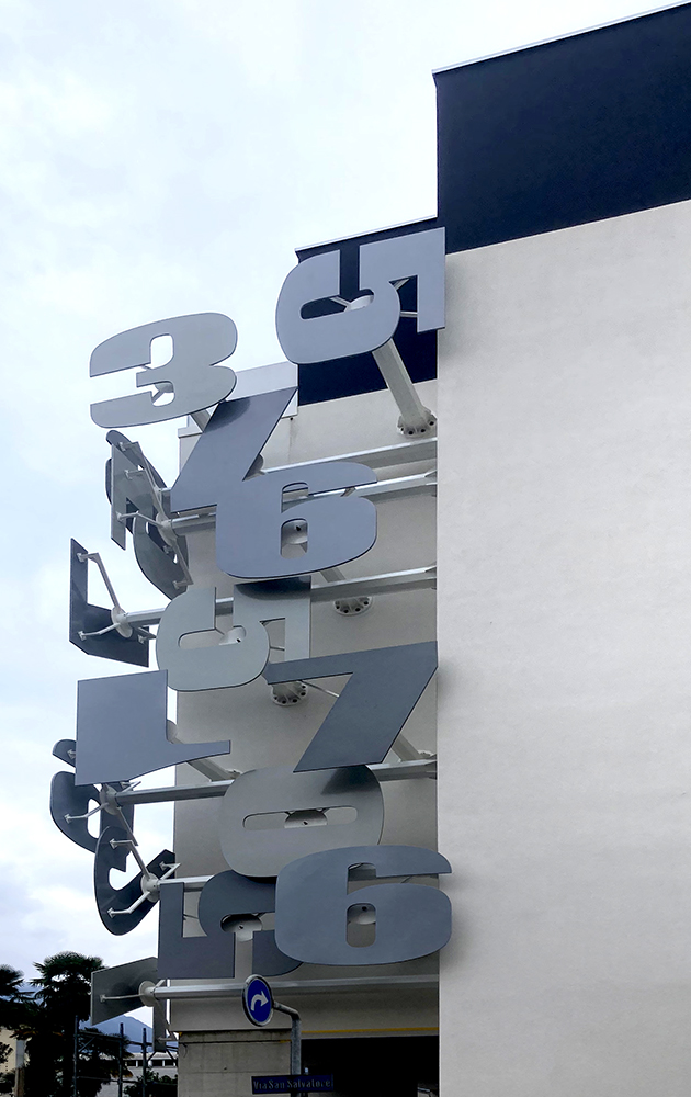 paolo grassi conceptual installation massagno side view bronze numeric sculpture facade