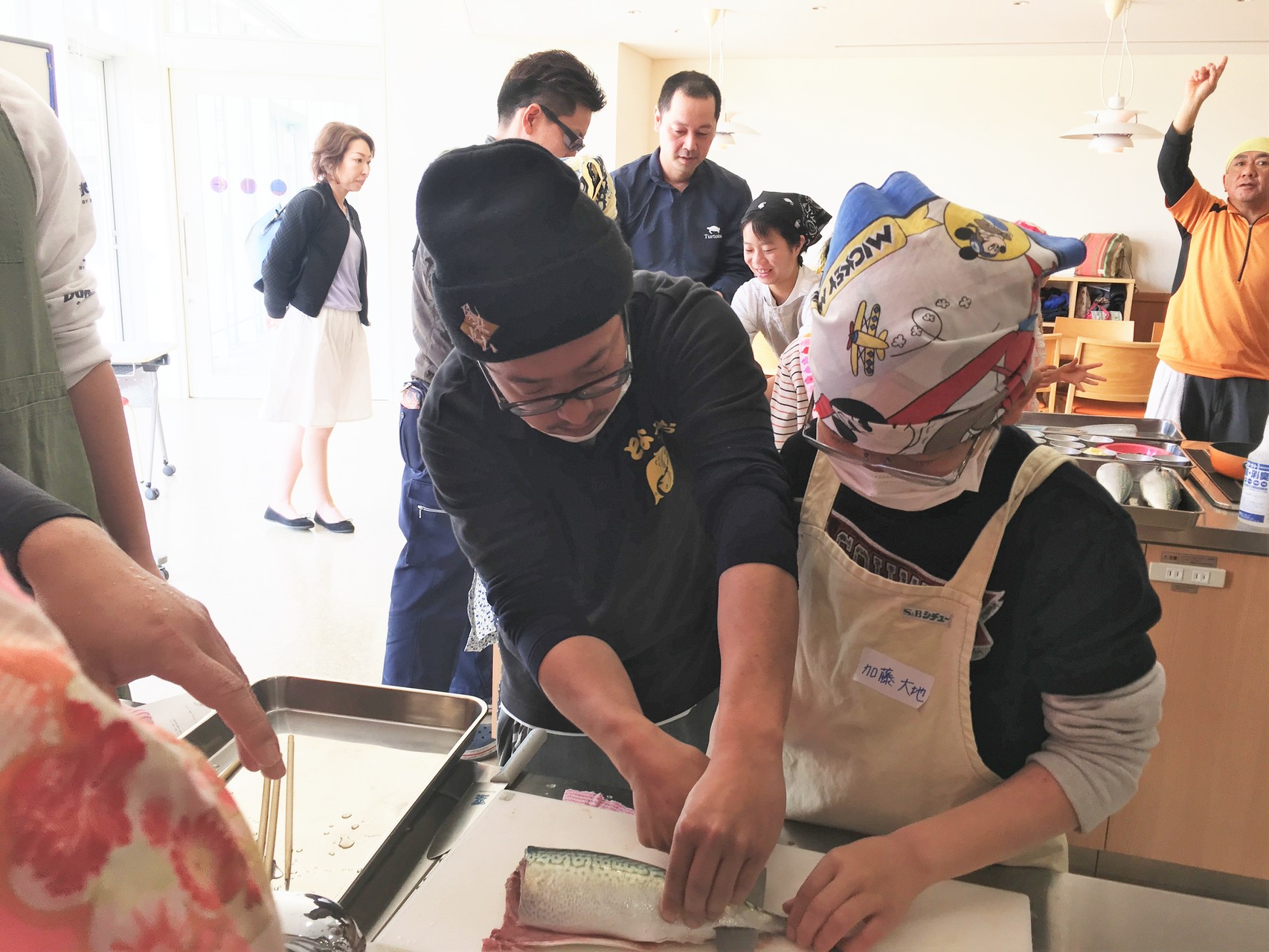 魚市場鮮魚部の山本洋さん（左端）の指導を受ける生徒。