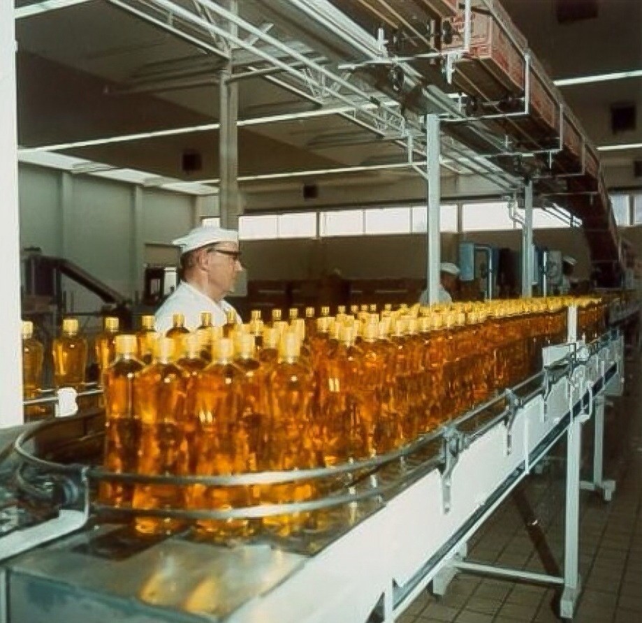 Medewerker aan de lopende band slaolieflessen in de Calvéfabrieken aan de Wateringseweg, 1975