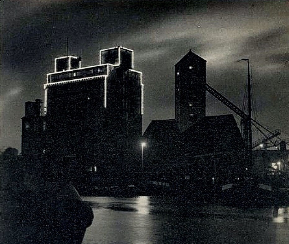 Gedeeltelijk verlichte silo (gesloopt eind 1995) van de Calvéfabriek aan de Wateringseweg bij avond. Rechts de lostoren. Deze verlichting werd in 1924 aangebracht. Bij de vergroting van de silo in 1938 werd de verlichting verwijderd. 1930