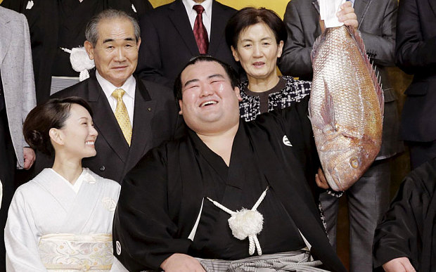 Sumo-wrestler Ozeki-Kotoshogiku holds up a sea bream as he celebrates his victory (01.2016)