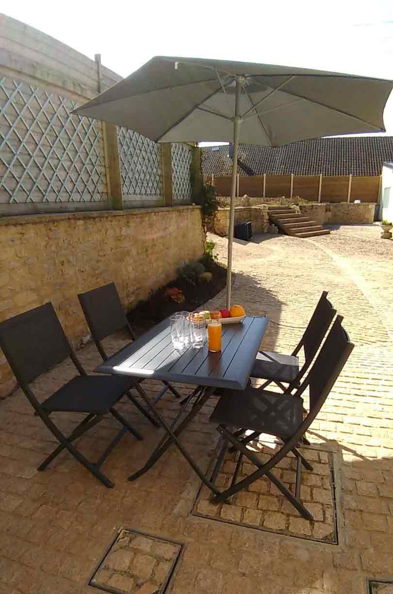 La terrasse privée du gîte avec ses chaises, sa table et son parasol