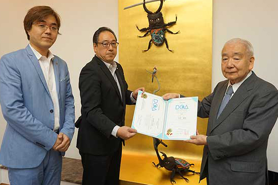 写真:DCA3級授与式の様子。写真中央がDCA3級の認定を受けた阿野越雄氏、左が株式会社コーエーテクモゲームス代表取締役社長鯉沼 久史氏、右がI-ROI代表理事 白鳥 令。
