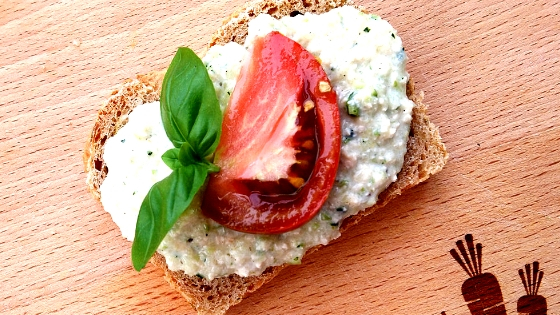 Foto einer Scheibe Zucchinibrot mit Zucchiniaufstrich und Kräuterdeko