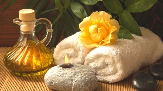 Kerze, Handtücher, Blume und Öl als Wellnessarrangement