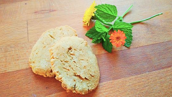 Zwei Hirseplätzchen an Blumen auf einer Holzplatte