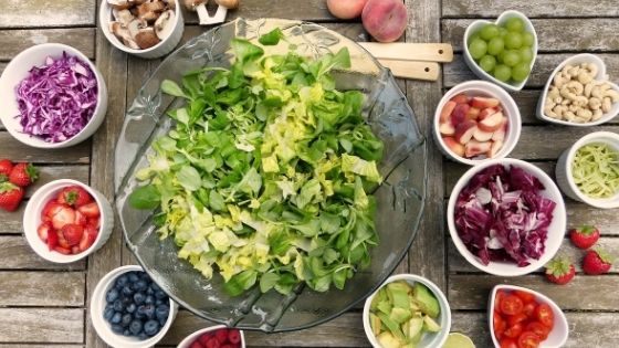 Rustikaler Holztisch mit Salatschüssel und Obstschüsselchen
