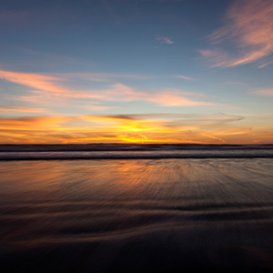 South Pacific Ocean Sunset with warm Colors and blurred Waves, New Zealand 