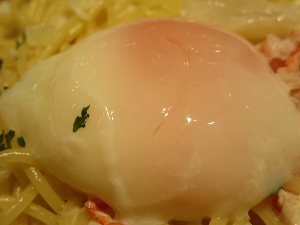 洋麺屋 五右衛門の紅ズワイガニと帆立のクリームソース 温泉卵添えの温泉玉子の近影画像。