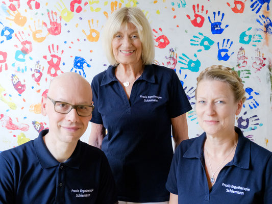 Teamfoto einer Praxis in Stuttgart mit drei Mitarbeitenden in einheitlicher Kleidung vor hellem Hintergrund, geeignet für Website und Unternehmensdarstellung